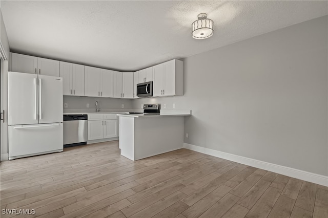 kitchen featuring white cabinets, appliances with stainless steel finishes, light wood-type flooring, and sink