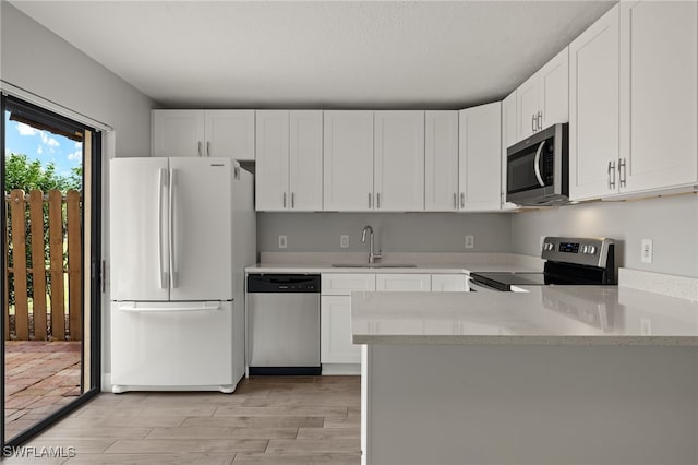 kitchen with white cabinets, sink, appliances with stainless steel finishes, and light hardwood / wood-style flooring