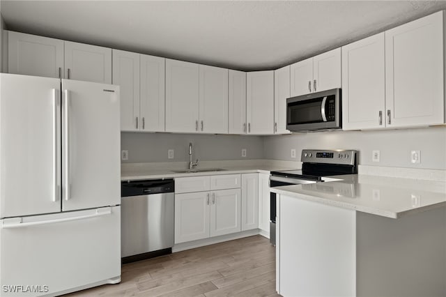 kitchen featuring white cabinetry, sink, light hardwood / wood-style floors, and appliances with stainless steel finishes