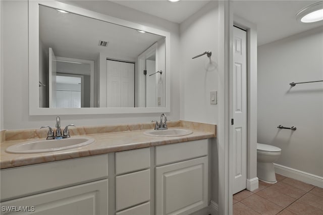 bathroom with toilet, vanity, and tile patterned floors