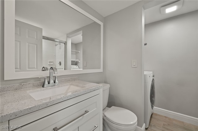 bathroom featuring vanity, wood-type flooring, toilet, a shower with shower door, and washer / clothes dryer