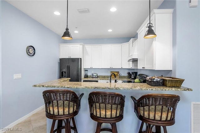 kitchen with kitchen peninsula, light stone counters, sink, black appliances, and white cabinetry