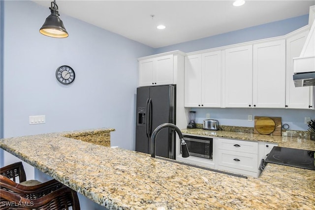 kitchen with white cabinets, pendant lighting, and black fridge