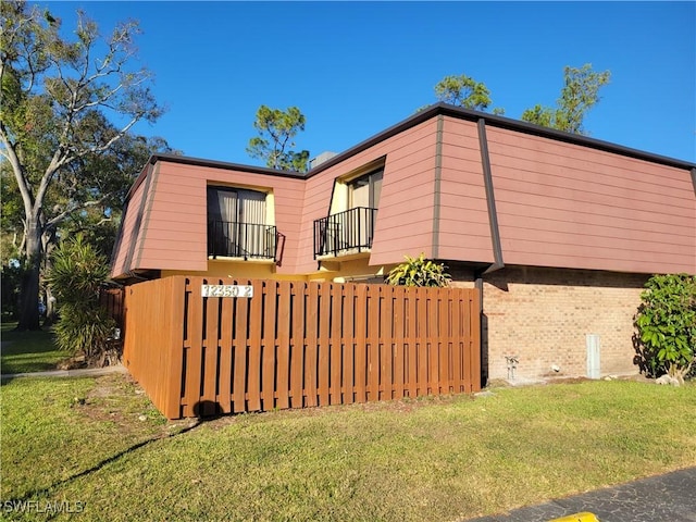 view of side of property featuring a lawn and a balcony