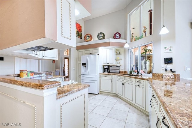 kitchen with pendant lighting, sink, white fridge with ice dispenser, light tile patterned floors, and kitchen peninsula