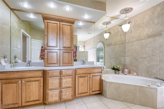 bathroom with tile patterned flooring, vanity, and tiled bath