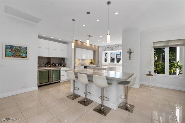 kitchen featuring white cabinets, plenty of natural light, backsplash, and decorative light fixtures