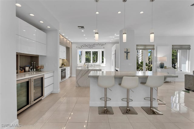 kitchen featuring pendant lighting, a breakfast bar, stainless steel oven, sink, and white cabinetry