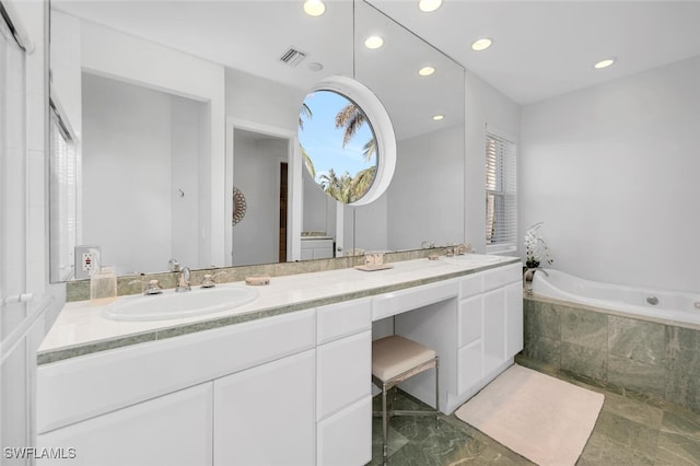 bathroom with tiled tub, plenty of natural light, and vanity