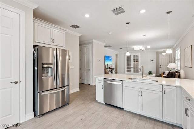 kitchen featuring pendant lighting, light wood-type flooring, stainless steel appliances, and white cabinetry