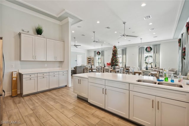 kitchen with ceiling fan, sink, crown molding, light hardwood / wood-style floors, and white cabinets