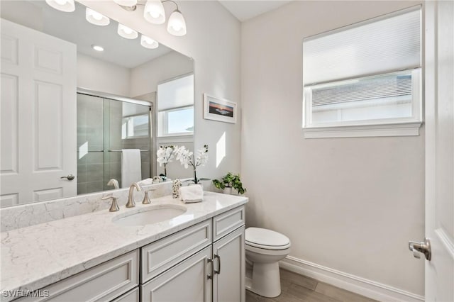 bathroom with hardwood / wood-style floors, vanity, toilet, and a shower with shower door