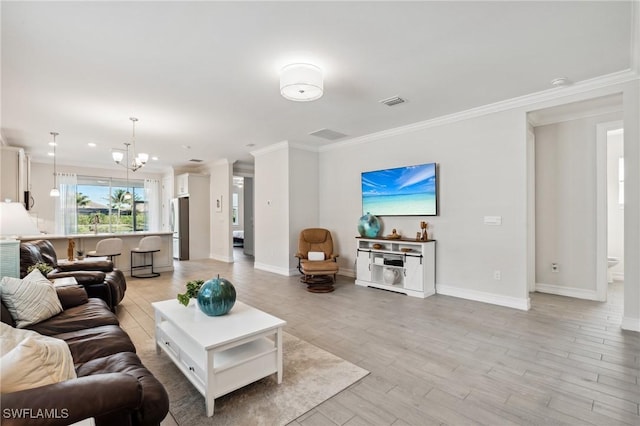 living room featuring light hardwood / wood-style floors, crown molding, and a notable chandelier