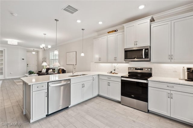 kitchen with white cabinetry, sink, kitchen peninsula, decorative light fixtures, and appliances with stainless steel finishes