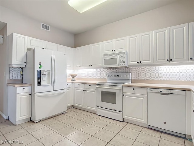 kitchen with backsplash, light tile patterned floors, white cabinets, and white appliances