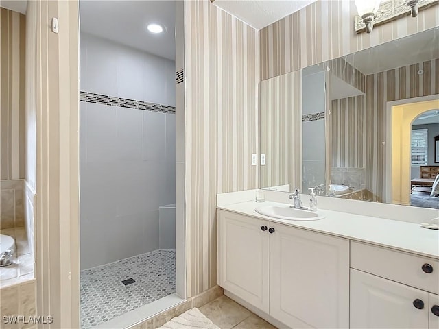 bathroom featuring tile patterned flooring, vanity, and tiled shower