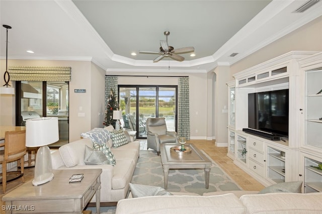 living room with a tray ceiling, ceiling fan, and crown molding