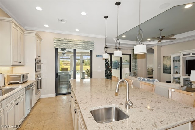 kitchen with a large island with sink, light stone counters, stainless steel dishwasher, and sink