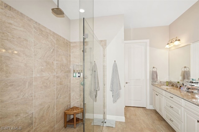 bathroom featuring tiled shower, vanity, and tile patterned flooring