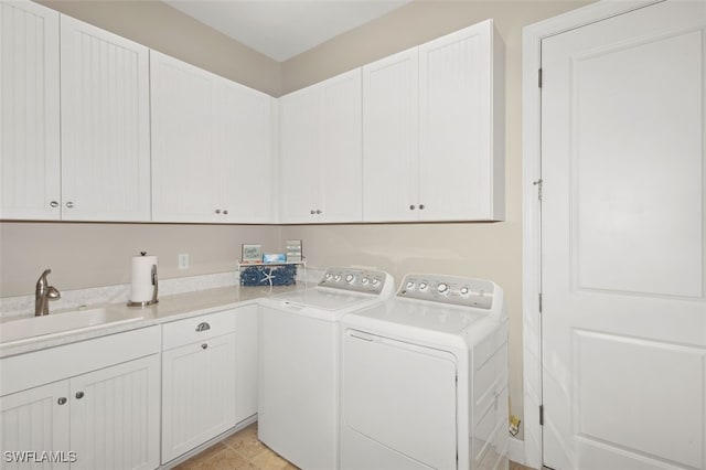 washroom featuring washing machine and clothes dryer, sink, light tile patterned floors, and cabinets