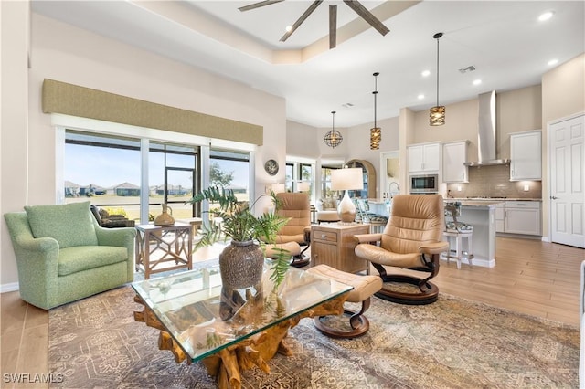 living room featuring a notable chandelier, light wood-type flooring, and a towering ceiling