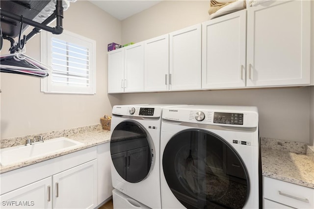 laundry room featuring cabinets, washer and clothes dryer, and sink