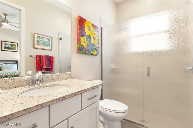 bathroom featuring ceiling fan, a shower with door, vanity, and toilet