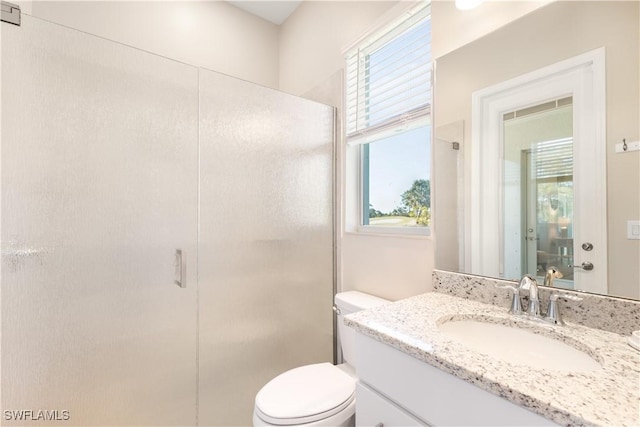 bathroom with vanity, toilet, and a shower with door