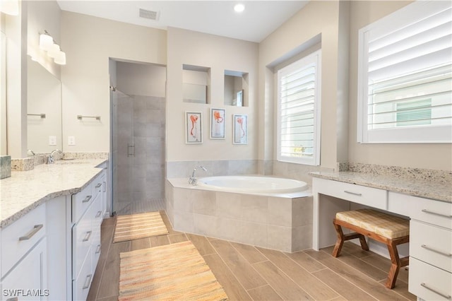 bathroom featuring plus walk in shower, vanity, and hardwood / wood-style flooring