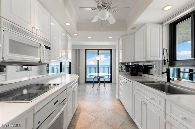 kitchen with white cabinets, white appliances, a wealth of natural light, and hanging light fixtures