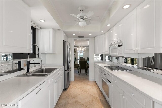 kitchen featuring white cabinets, appliances with stainless steel finishes, a raised ceiling, and sink