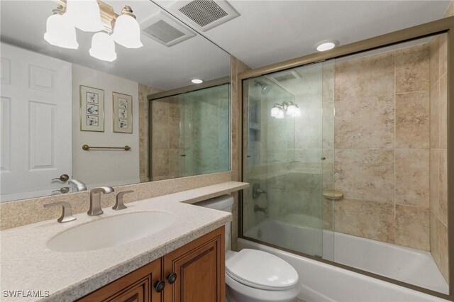 full bathroom with combined bath / shower with glass door, vanity, and toilet