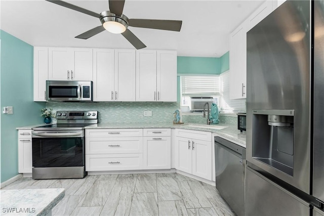 kitchen with backsplash, ceiling fan, light stone countertops, white cabinetry, and stainless steel appliances