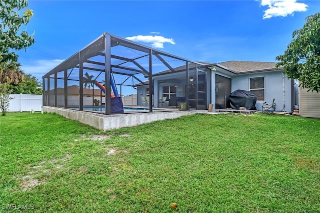 back of property with a fenced in pool, glass enclosure, and a yard