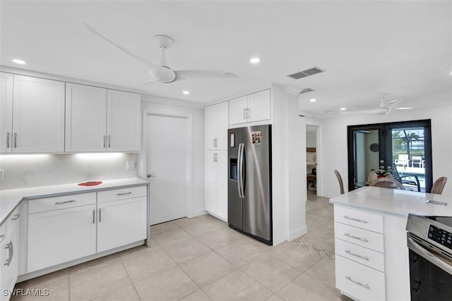 kitchen featuring ceiling fan, light tile patterned floors, backsplash, white cabinets, and appliances with stainless steel finishes