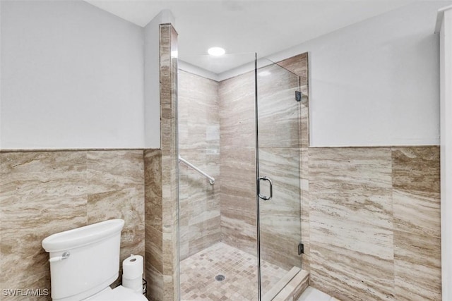 bathroom with toilet, a shower with shower door, and tile walls