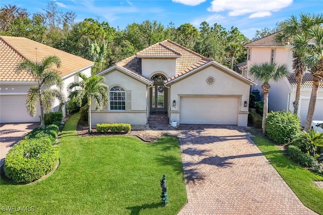 mediterranean / spanish home with decorative driveway, a tile roof, an attached garage, and stucco siding