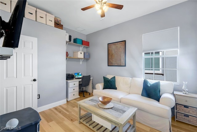 living room featuring baseboards, light wood-type flooring, and ceiling fan