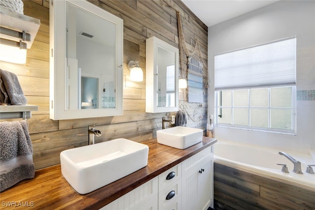 bathroom with visible vents, a sink, wooden walls, and a bath