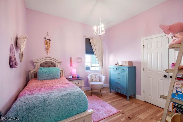 bedroom with an inviting chandelier, baseboards, and wood finished floors