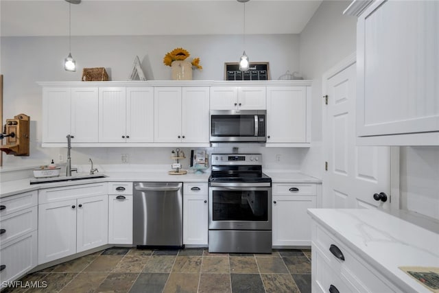 kitchen with white cabinets, stone finish floor, pendant lighting, and stainless steel appliances