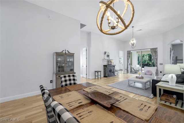 living room featuring a chandelier, arched walkways, light wood-style flooring, and baseboards