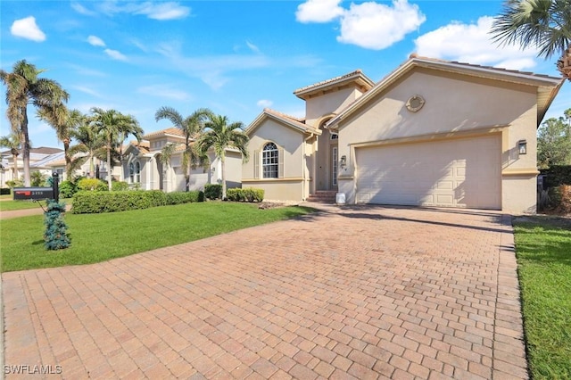 mediterranean / spanish house with a front lawn, decorative driveway, an attached garage, and stucco siding