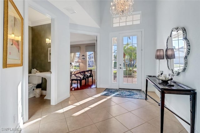 tiled entryway featuring ornamental molding and a chandelier