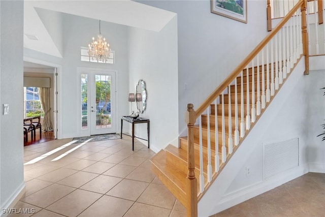 foyer entrance featuring light tile patterned floors, french doors, a notable chandelier, and a high ceiling