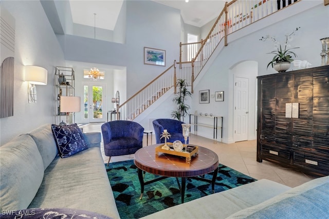 living room featuring french doors, light tile patterned flooring, a high ceiling, and a notable chandelier