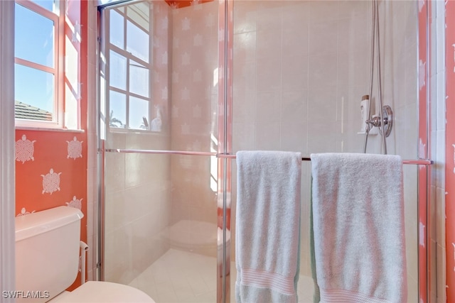 bathroom featuring toilet and a shower with shower door