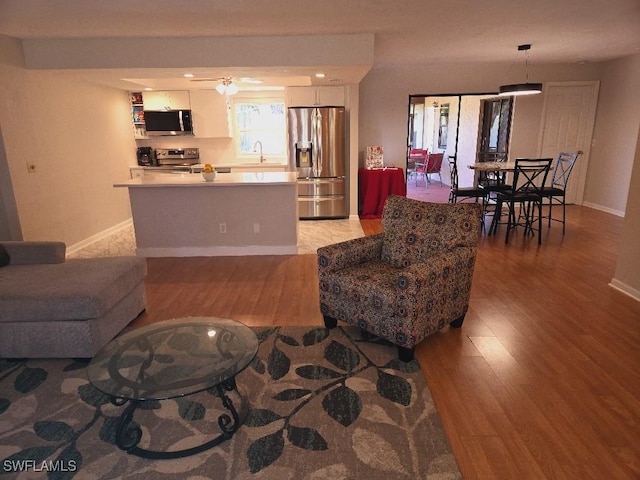 living room with light hardwood / wood-style floors, ceiling fan, and sink