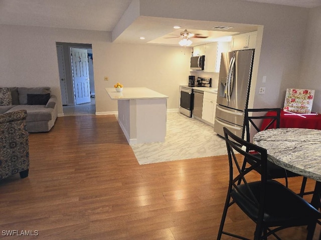 kitchen with ceiling fan, light hardwood / wood-style floors, white cabinetry, and appliances with stainless steel finishes