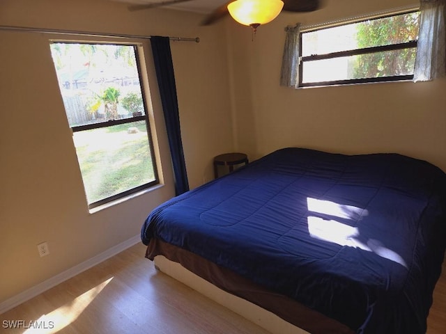 bedroom featuring wood-type flooring, multiple windows, and ceiling fan